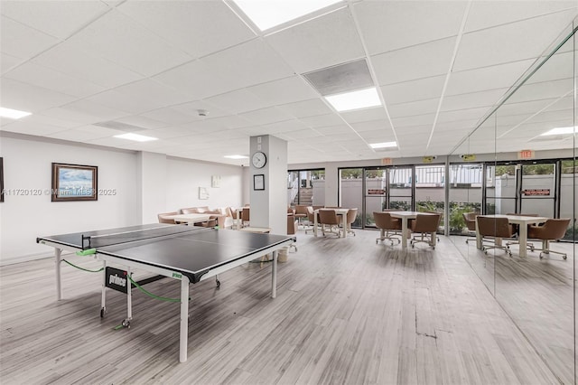 playroom with a paneled ceiling, light hardwood / wood-style floors, and a wall of windows