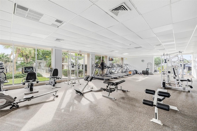 exercise room with floor to ceiling windows and a drop ceiling