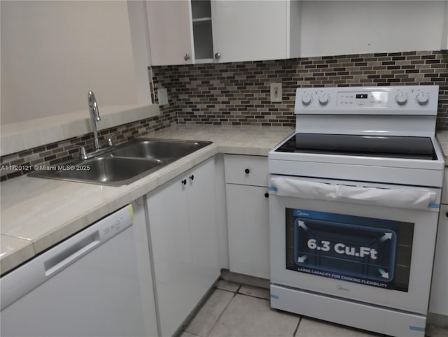 kitchen with white appliances, sink, light tile patterned floors, tasteful backsplash, and white cabinetry