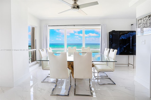 dining room with ceiling fan, a water view, and plenty of natural light