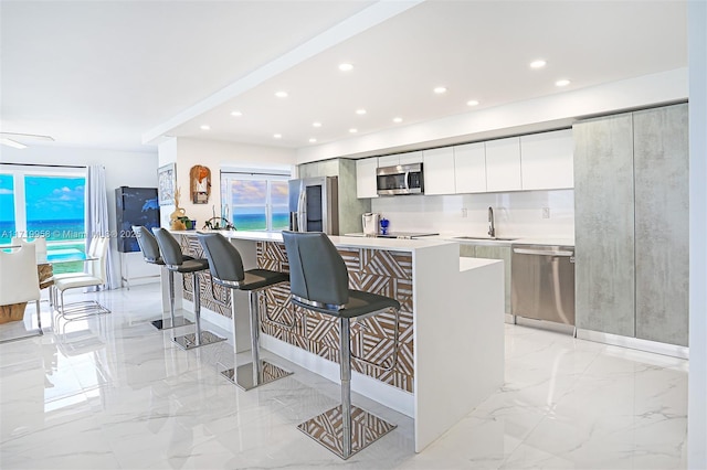 kitchen with white cabinets, a kitchen breakfast bar, sink, a kitchen island, and stainless steel appliances