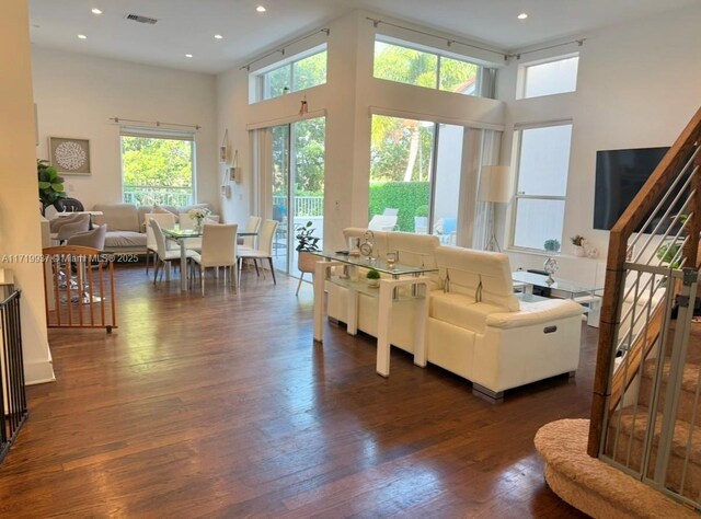 living room featuring a towering ceiling and dark hardwood / wood-style floors