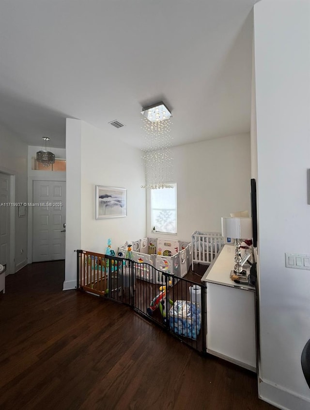 hall featuring baseboards, visible vents, and wood finished floors