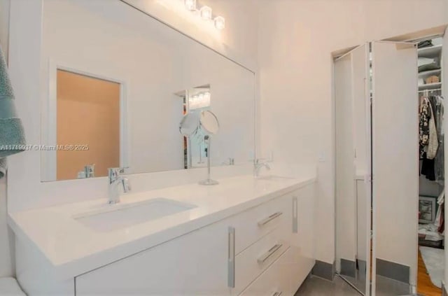 full bathroom featuring double vanity, a spacious closet, and a sink