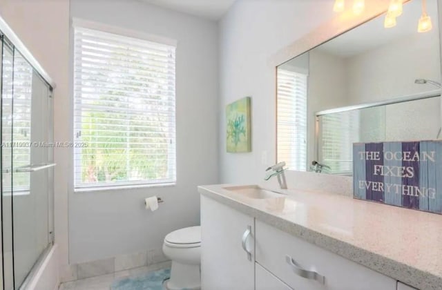 full bath featuring baseboards, shower / bath combination with glass door, vanity, and toilet