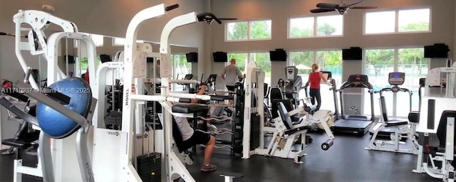 workout area featuring a ceiling fan and a high ceiling