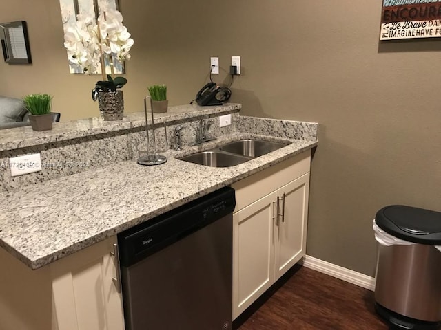 kitchen featuring stainless steel dishwasher, light stone counters, dark wood-type flooring, sink, and white cabinetry