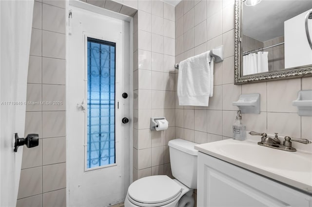 bathroom with vanity, tasteful backsplash, toilet, and tile walls