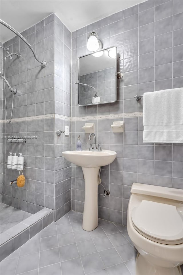 bathroom featuring a tile shower, tile patterned floors, tile walls, and toilet