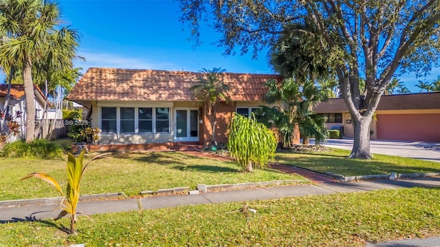 ranch-style house featuring a garage and a front lawn