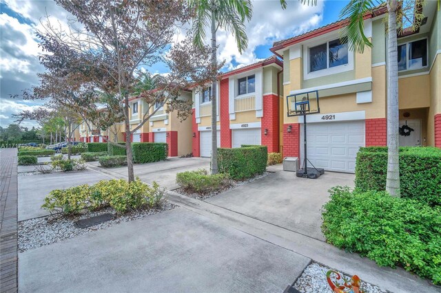 4923 SW 66th Ter Unit 4923, Davie, FL 33314 - view of front of property featuring an attached garage, stucco siding, driveway, a residential view, and brick siding