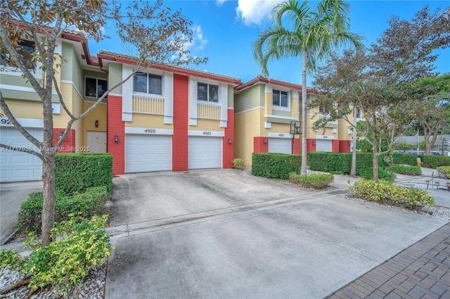 multi unit property featuring driveway, brick siding, an attached garage, and stucco siding