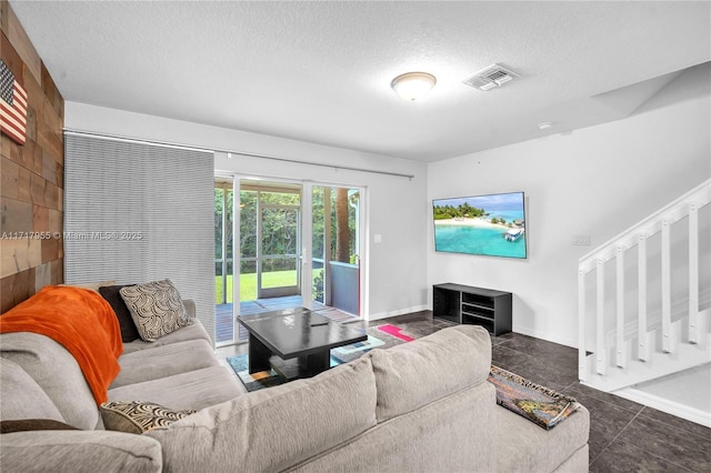 living area with a textured ceiling, visible vents, and baseboards