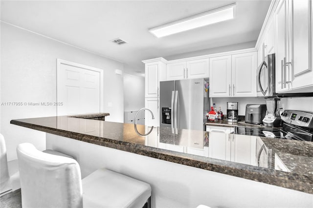 4923 SW 66th Ter Unit 4923, Davie, FL 33314 - kitchen with dark stone counters, stainless steel appliances, white cabinets, visible vents, and a kitchen breakfast bar