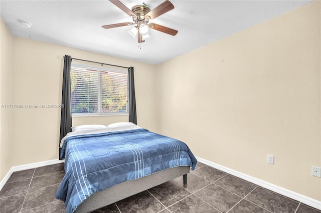 bedroom with dark tile patterned flooring, a ceiling fan, and baseboards