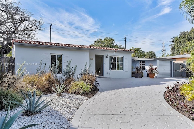 mediterranean / spanish-style home with a garage, concrete driveway, a tile roof, and stucco siding