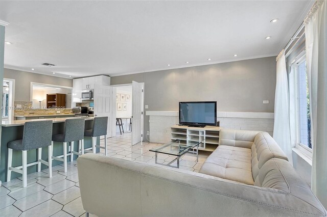 tiled living room featuring a wealth of natural light and ornamental molding