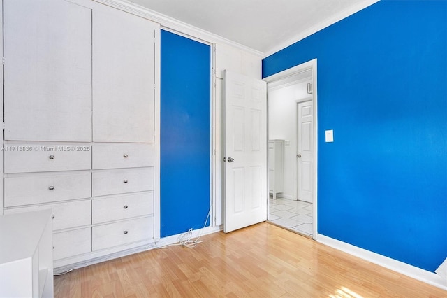 unfurnished bedroom with baseboards, light wood-style flooring, and crown molding