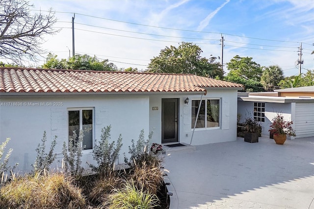 mediterranean / spanish home featuring a patio area, a tile roof, and stucco siding