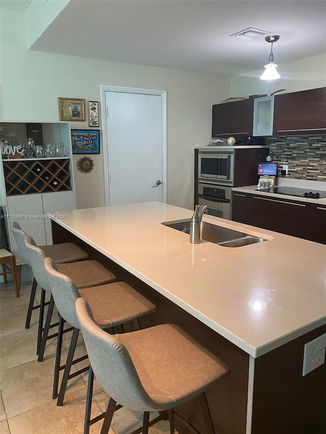 kitchen featuring a breakfast bar area, sink, hanging light fixtures, and stainless steel appliances