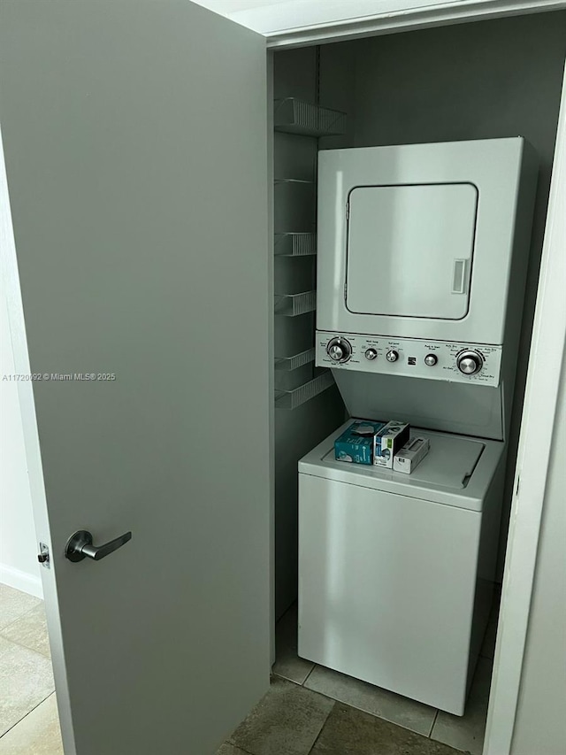 laundry area featuring light tile patterned floors and stacked washer and clothes dryer