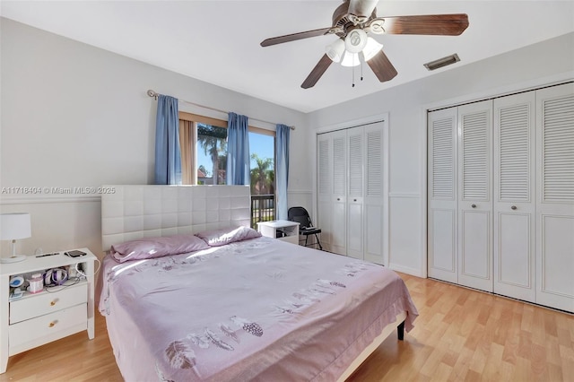 bedroom featuring ceiling fan, light hardwood / wood-style floors, and multiple closets