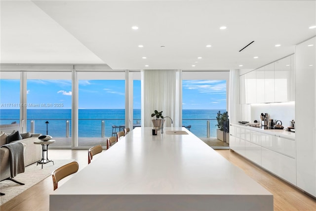 kitchen featuring a water view, light hardwood / wood-style flooring, floor to ceiling windows, and sink