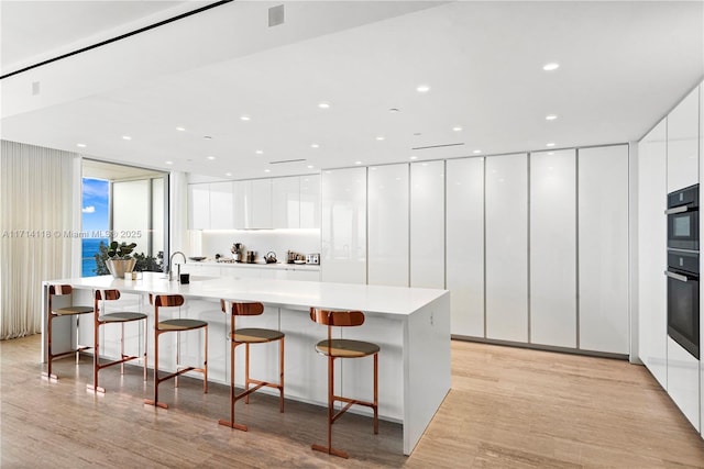 kitchen with a kitchen bar, white cabinetry, and a wall of windows