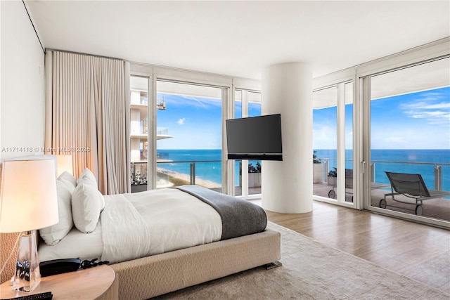 bedroom featuring hardwood / wood-style flooring, a wall of windows, and access to outside