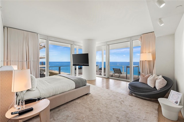 bedroom with hardwood / wood-style flooring, expansive windows, and access to exterior