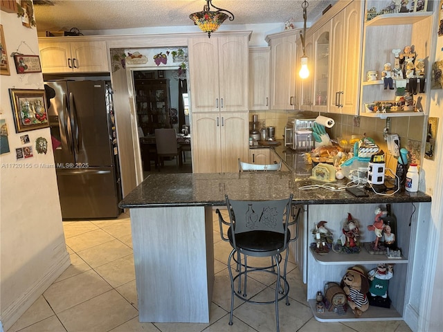 kitchen with a breakfast bar, stainless steel refrigerator with ice dispenser, kitchen peninsula, and light tile patterned flooring