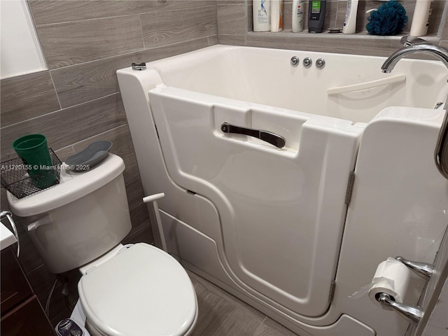 bathroom with toilet and tile walls