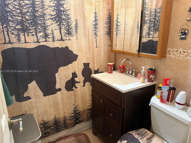 bathroom featuring tile patterned floors, vanity, toilet, and tile walls