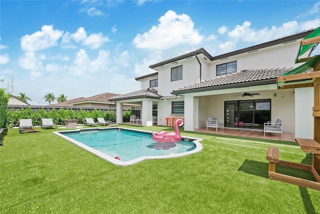 rear view of property with a patio, a fenced in pool, ceiling fan, and a lawn