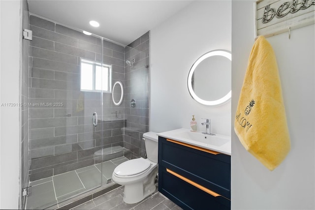 bathroom with tile patterned floors, vanity, toilet, and a shower with door