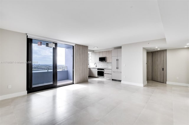 unfurnished living room featuring expansive windows and sink