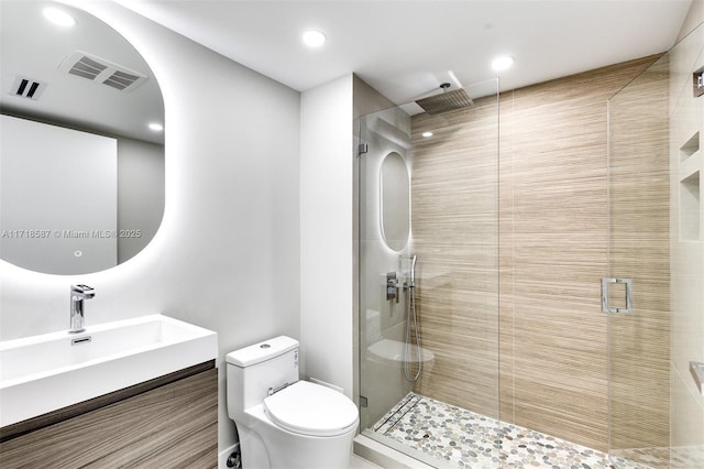 bathroom featuring vanity, a shower with shower door, and toilet