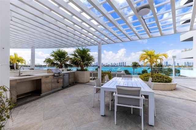 view of patio / terrace featuring a water view, a pergola, sink, a grill, and exterior kitchen