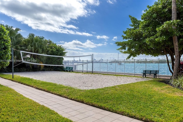 view of property's community with volleyball court, a yard, and a water view