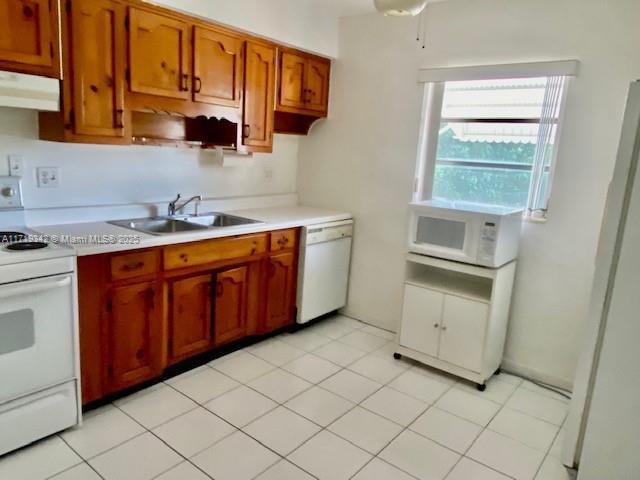 kitchen featuring sink, white appliances, light tile patterned floors, and ceiling fan