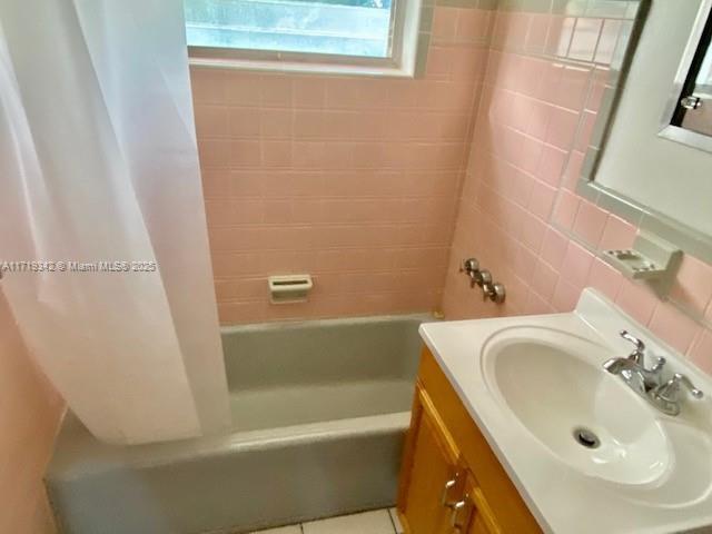 bathroom with tile walls, decorative backsplash, tile patterned flooring, vanity, and shower / bath combo