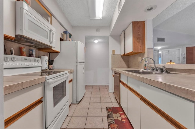 kitchen featuring backsplash, white appliances, sink, light tile patterned floors, and white cabinetry