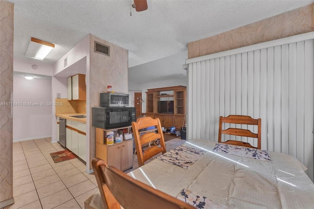 kitchen with ceiling fan, sink, a textured ceiling, light tile patterned flooring, and appliances with stainless steel finishes