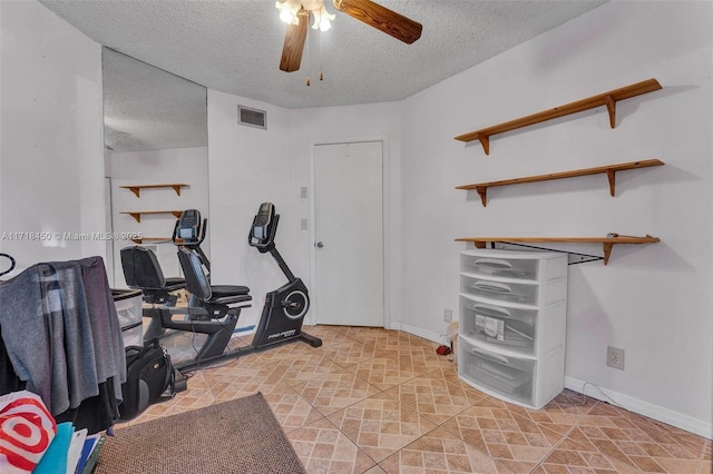 exercise area with ceiling fan and a textured ceiling