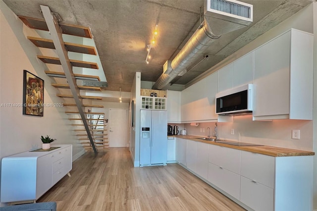 kitchen featuring white cabinetry, light hardwood / wood-style flooring, white appliances, and sink