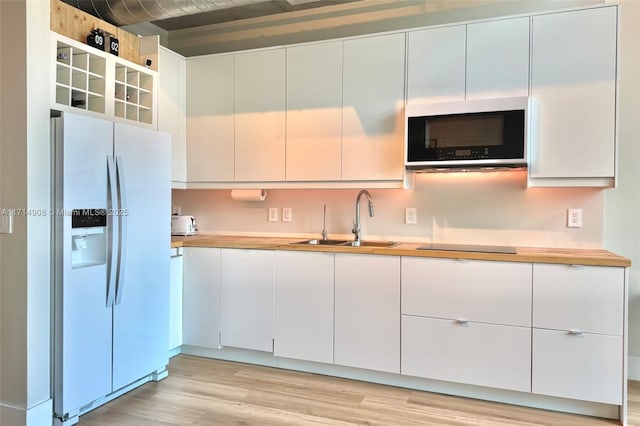 kitchen featuring white cabinetry, sink, light hardwood / wood-style floors, and white refrigerator with ice dispenser