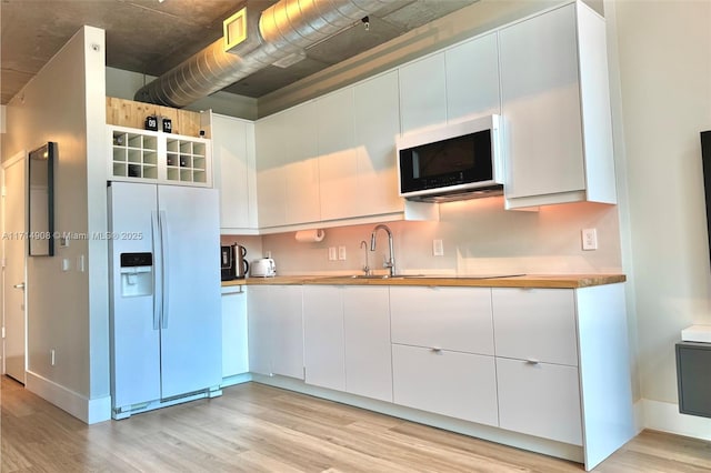 kitchen featuring white cabinets, light hardwood / wood-style floors, and white fridge with ice dispenser
