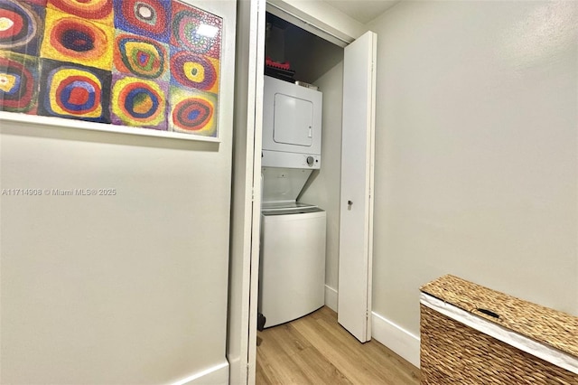 clothes washing area featuring light wood-type flooring and stacked washer / dryer
