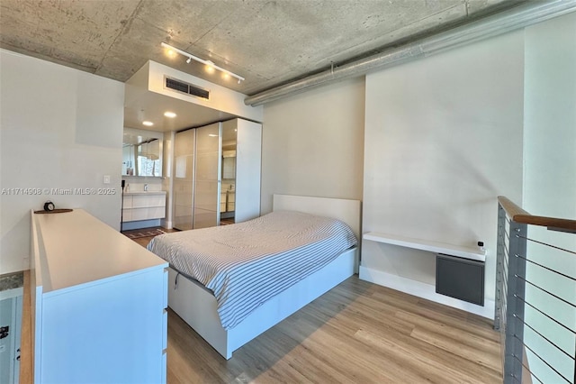 bedroom with a closet, light hardwood / wood-style flooring, and rail lighting