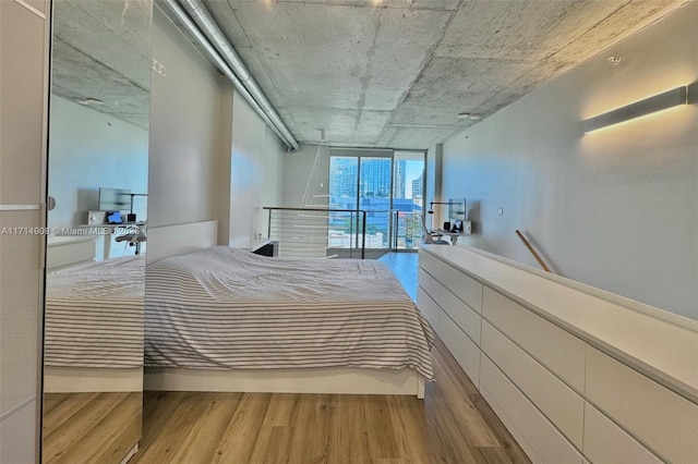 bedroom with hardwood / wood-style floors and a wall of windows